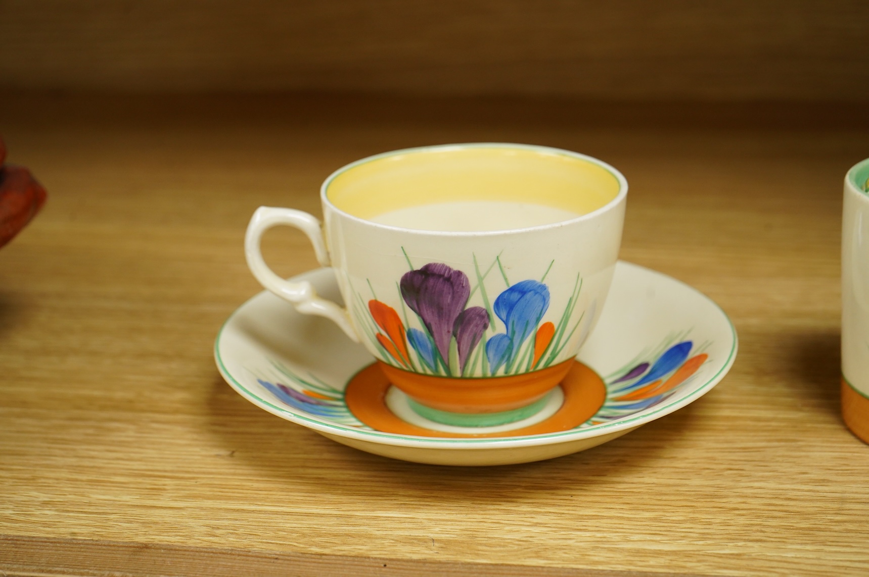 A Clarice Cliff ‘crocus’ pattern preserve jar and cover, 10cm high and a similar cup and saucer